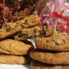Gift bag of gourmet cookies featuring a red ribbon and matching filler