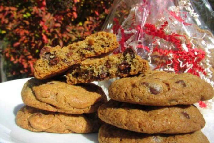 Gift bag of gourmet cookies featuring a red ribbon and matching filler